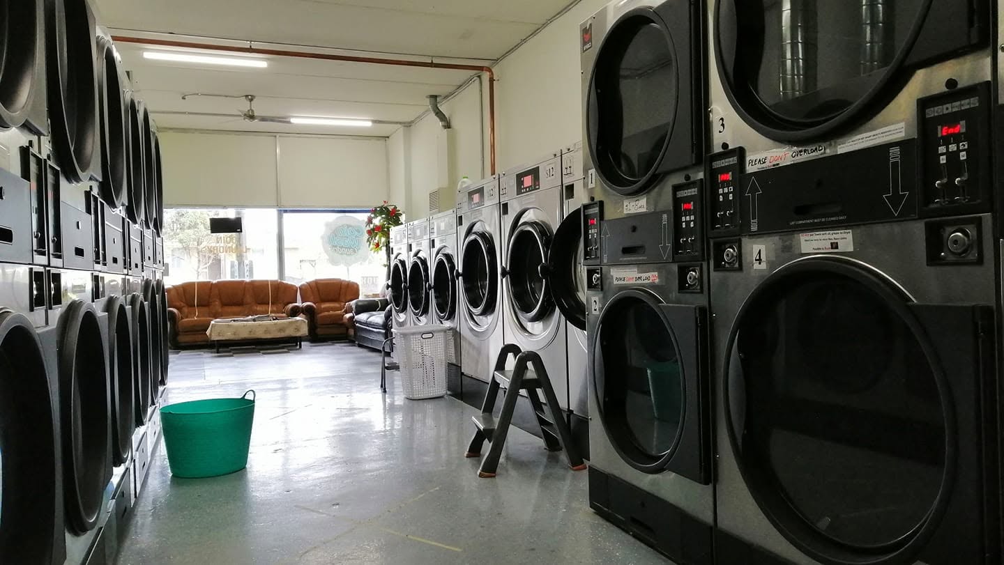 Interior view of Chandler Coin Laundry with rows of dryers and a lounge area