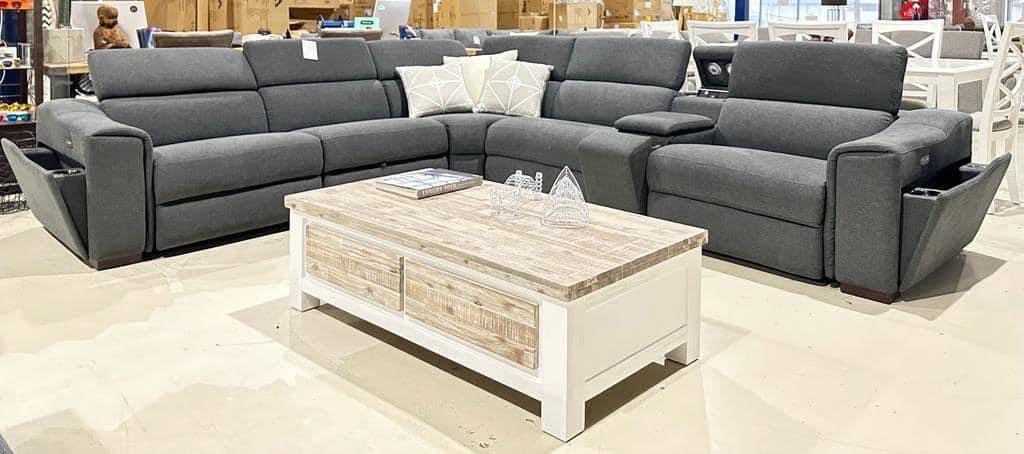 Dark grey corner recliner sofa with a timber coffee table on a showroom floor