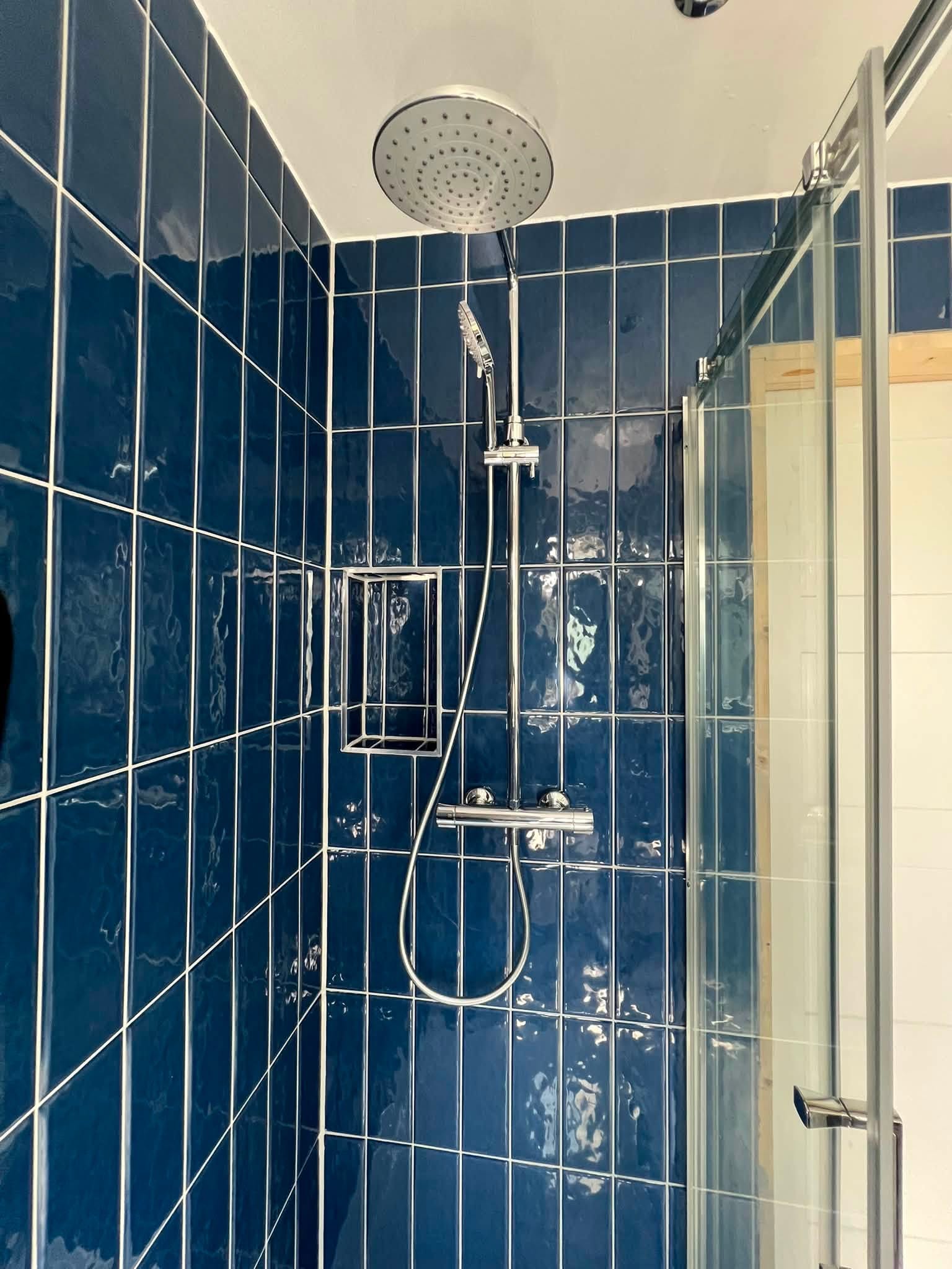 Chrome rainfall shower head against deep-blue wall tiles