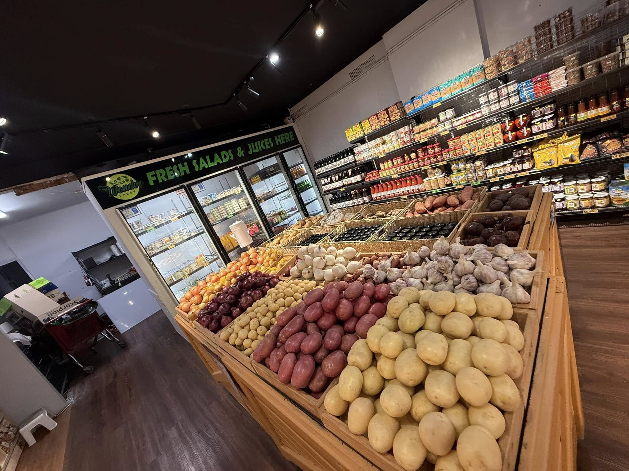 Fresh potatoes, onions and root vegetables in wooden display crates
