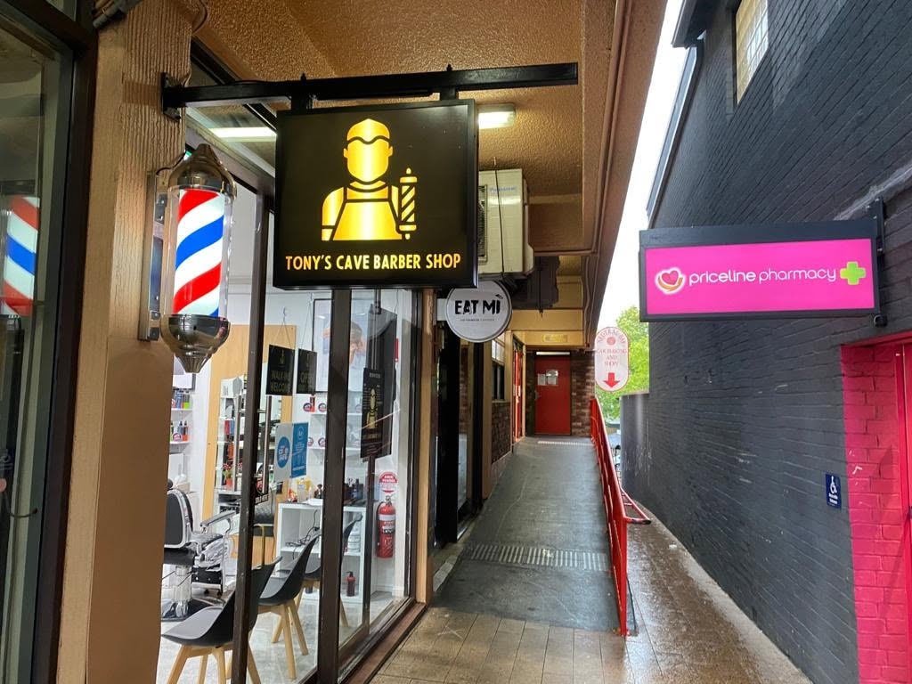Tony's Cave Barber Shop storefront with barber pole and illuminated sign