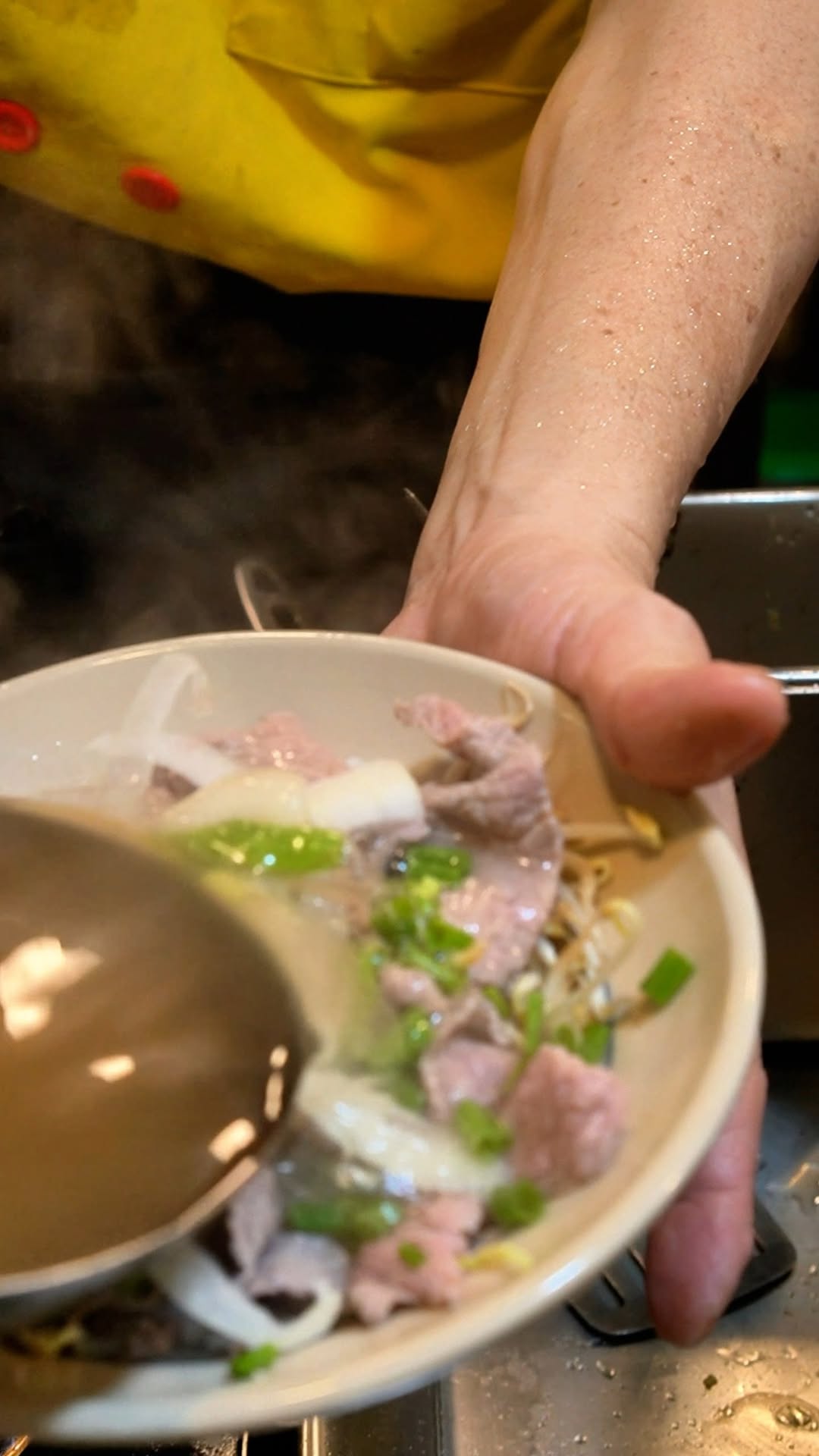 Hot pho broth being ladled into a bowl — freshly made at Đại Việt