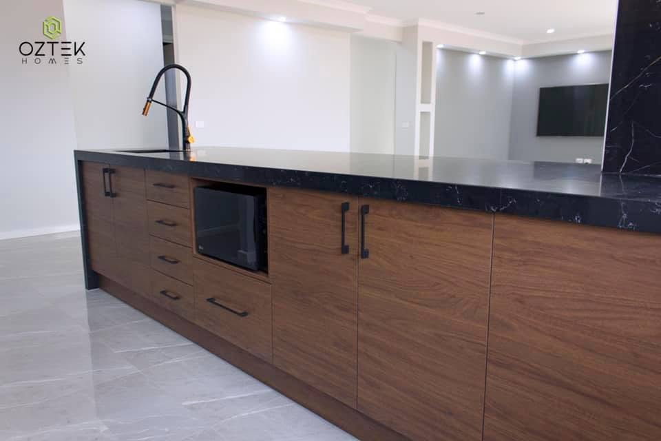 Premium kitchen island with walnut timber cabinetry and polished black marble benchtop