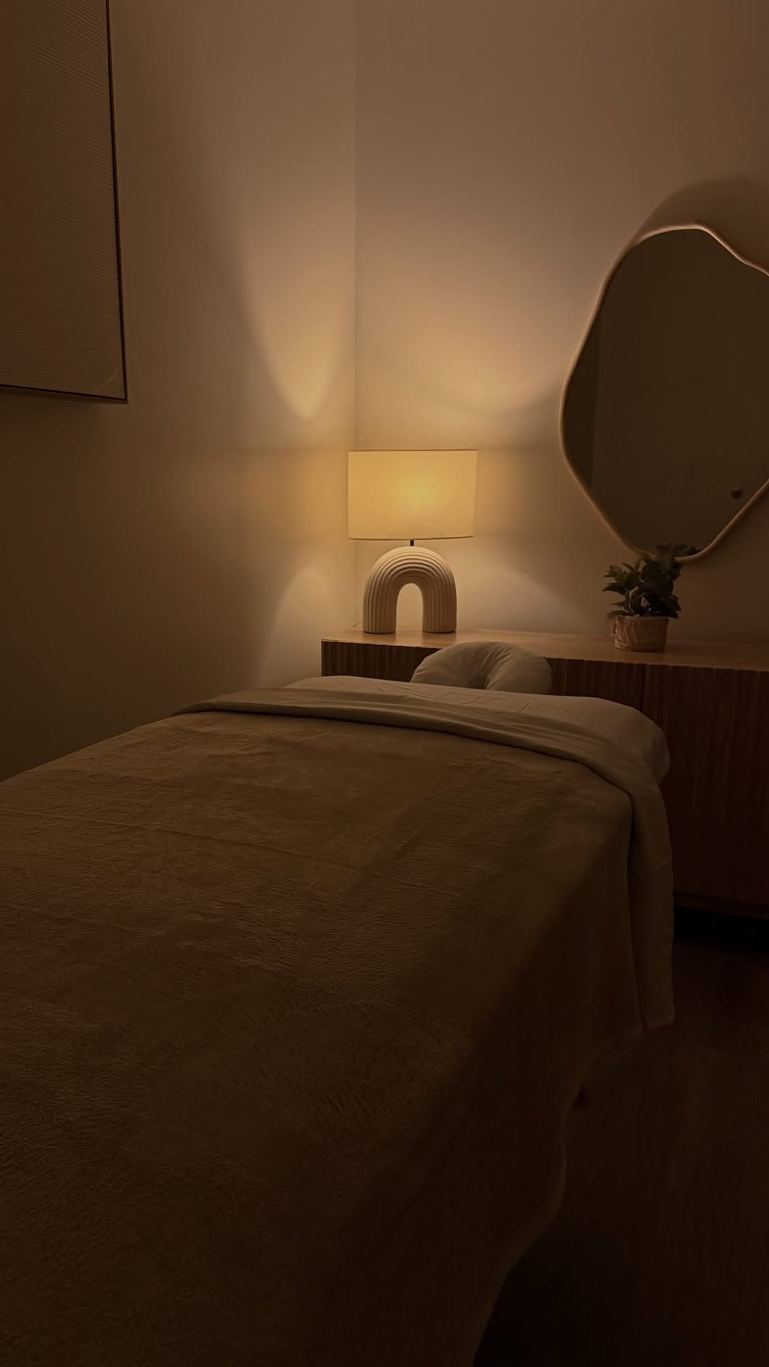 Softly lit treatment room with arch lamp and organic round mirror at Zen Tara