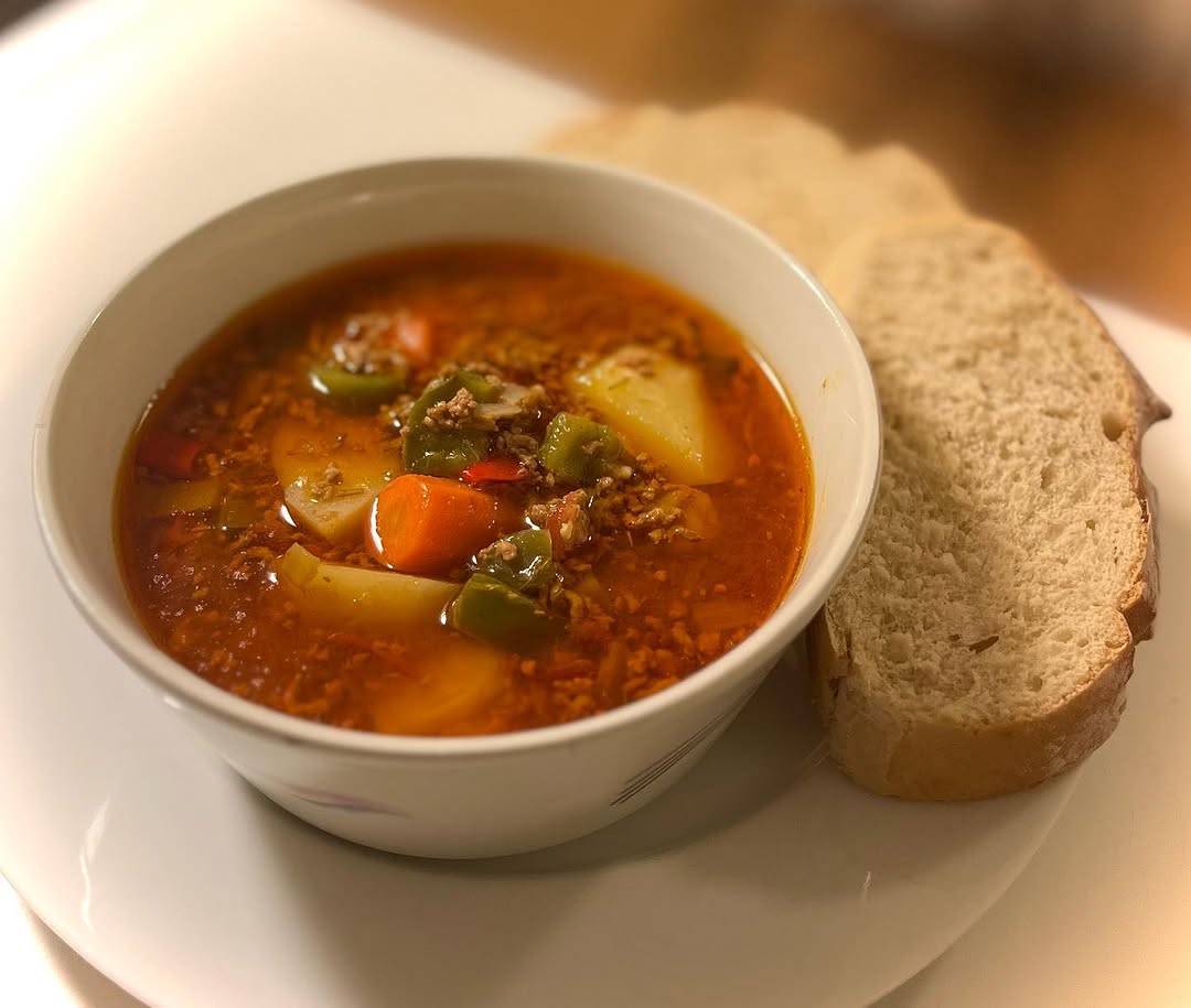 Hearty vegetable and meat soup served with crusty sourdough bread