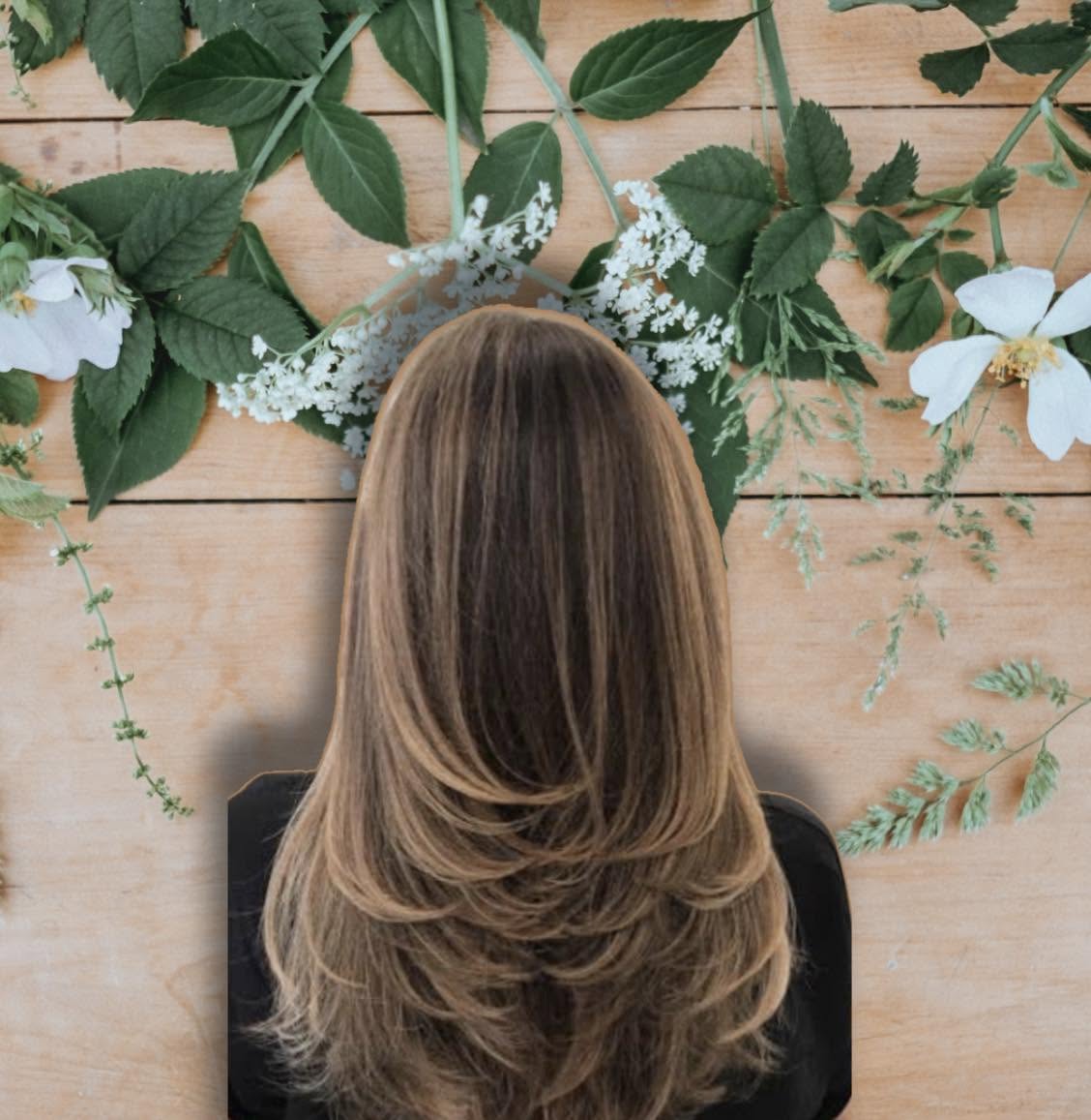 Layered brown hair with warm caramel highlights on a floral backdrop