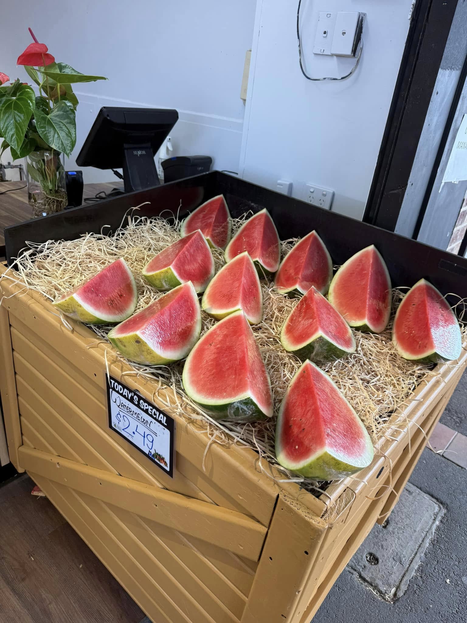 Fresh watermelon wedges displayed in a rustic wooden bin