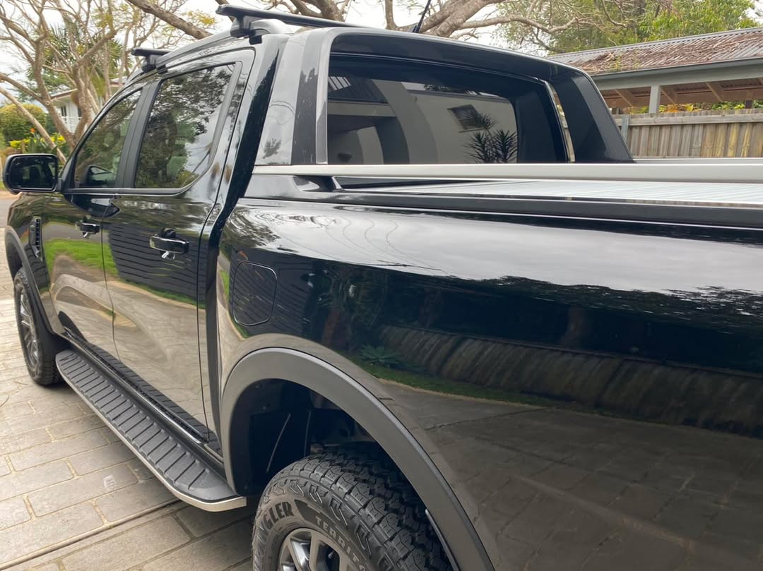 Black dual-cab ute with tinted rear windows and tray canopy