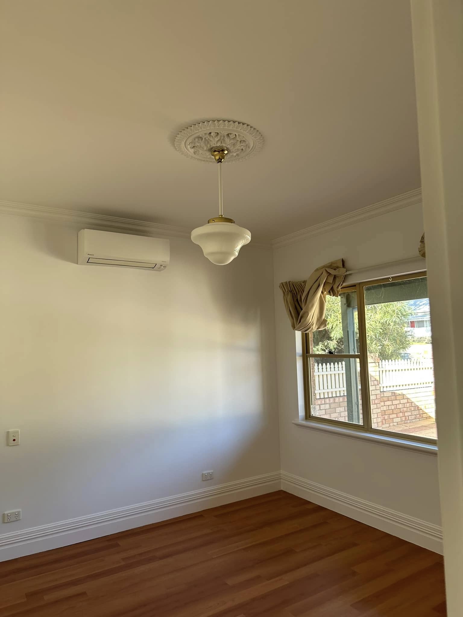 Freshly painted warm cream room with ornate ceiling rose, pendant light and timber floors