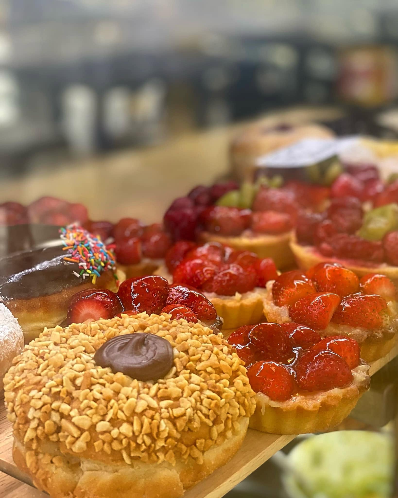 Colourful fruit tarts and doughnuts on a wooden board at Jorge's Cafe