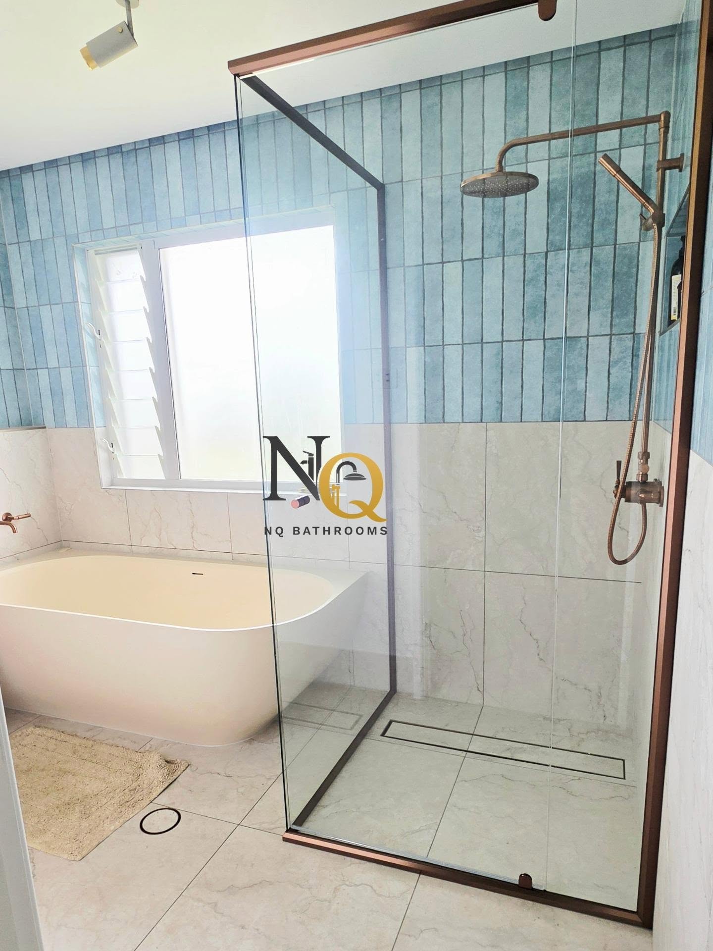 Bathroom renovation with teal vertical tiles, freestanding bath and copper-framed glass shower screen