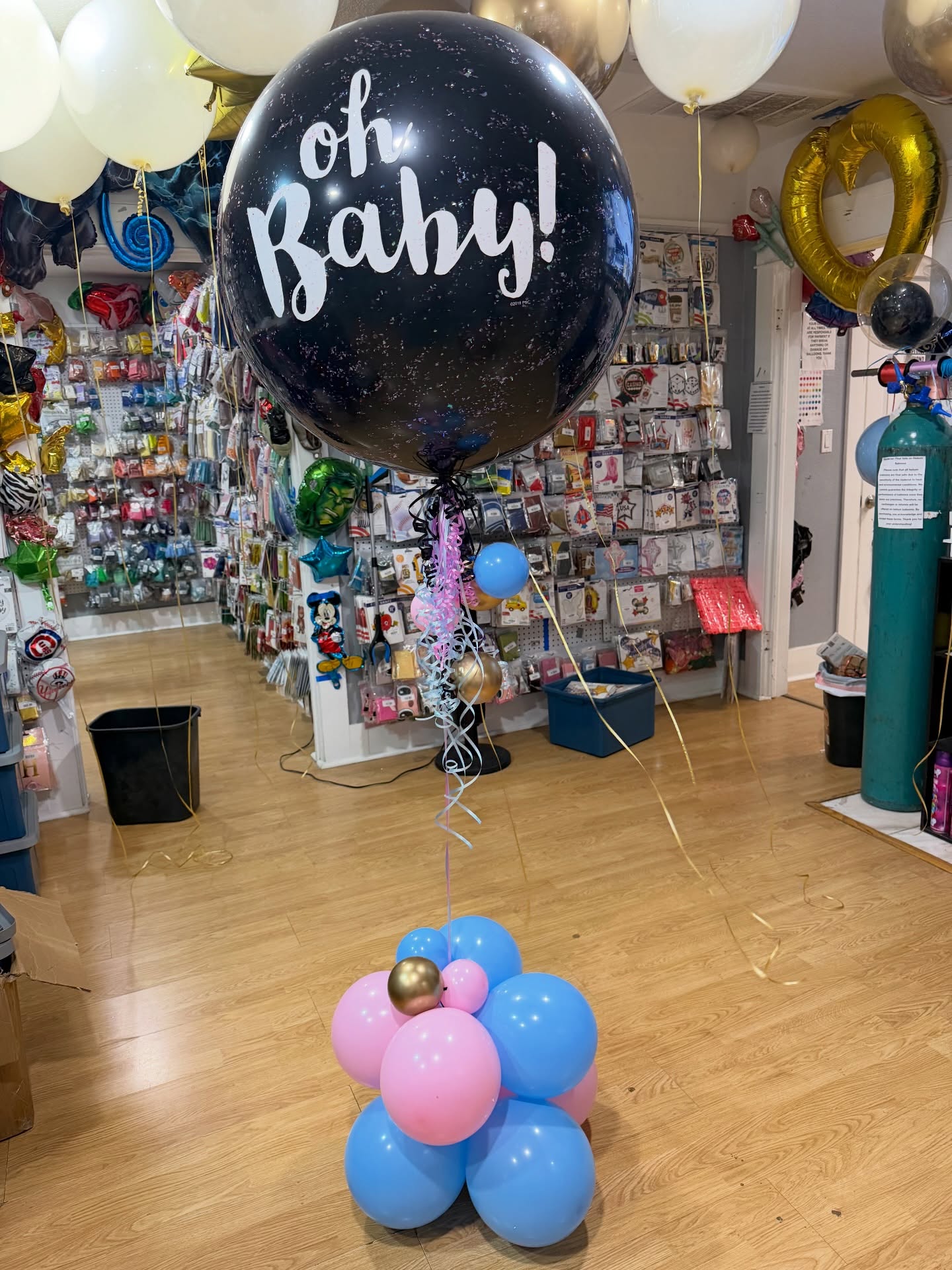 A large round balloon display reading 'Oh Baby' above a pink, blue and gold balloon base