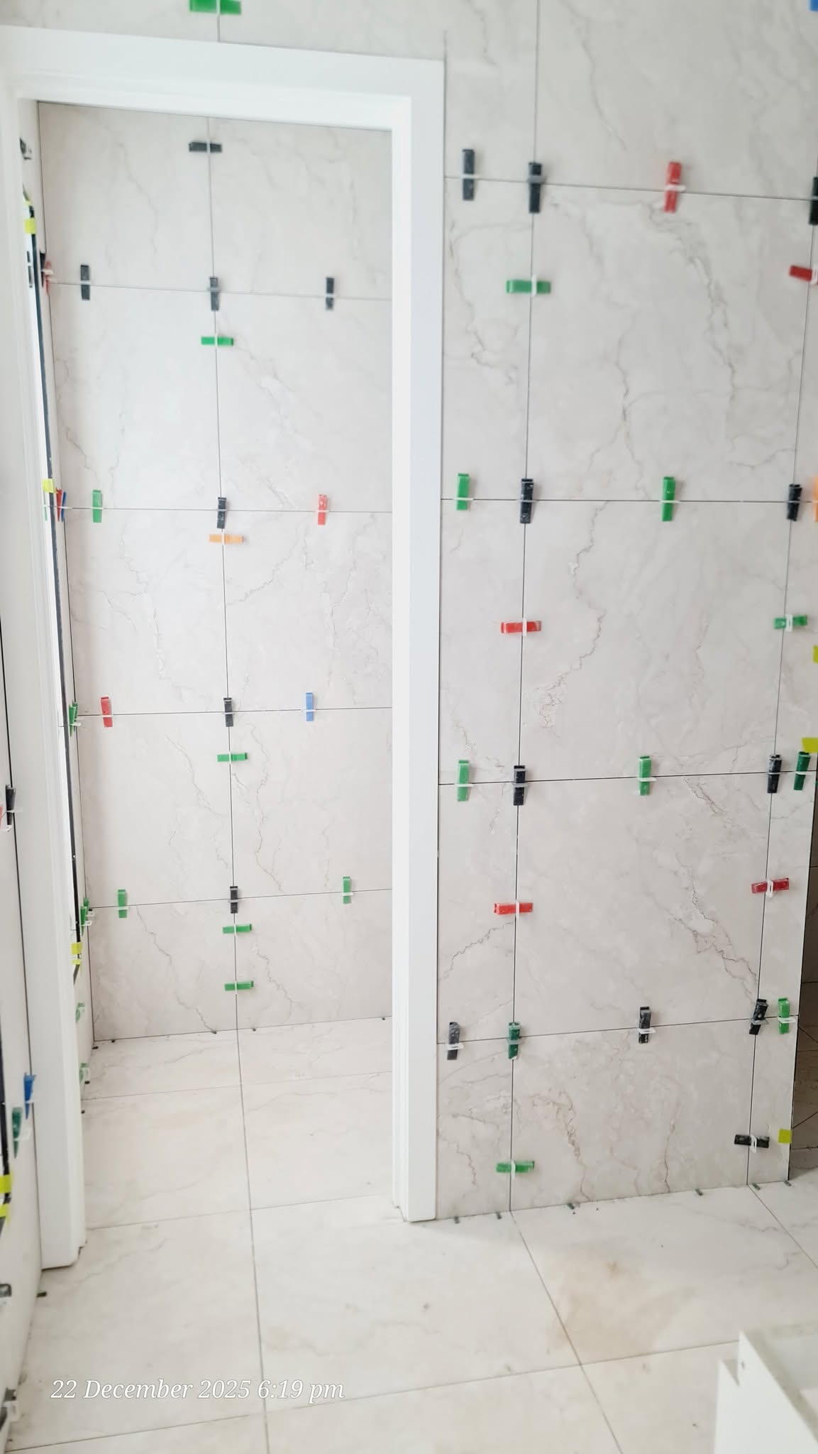 White marble-look wall tiles with perfect grout spacing around doorframe