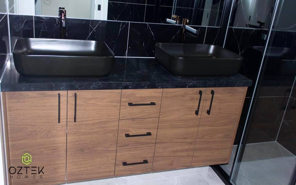 Luxury ensuite bathroom with double black vessel sinks and black marble tiling