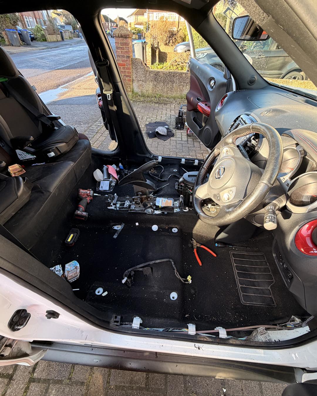 Car interior with the carpet and trim removed, parked at the kerb of a suburban street