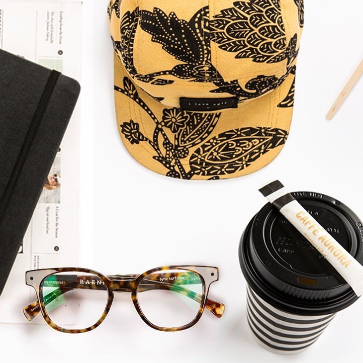 Caffè Aurora branded takeaway cup alongside lifestyle accessories on a white surface