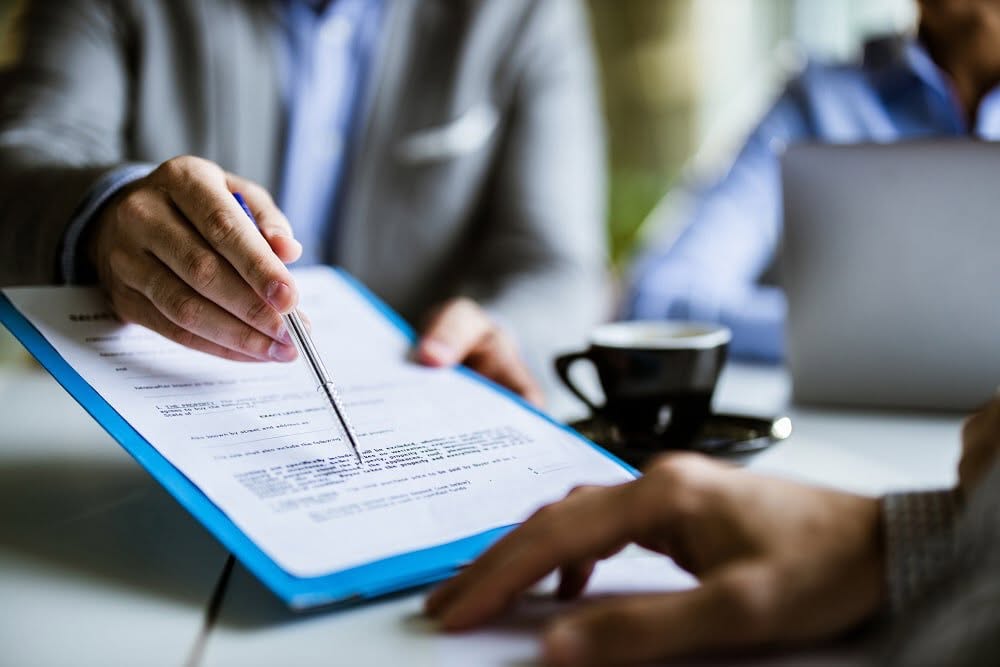 Financial adviser reviewing documents with a client over coffee