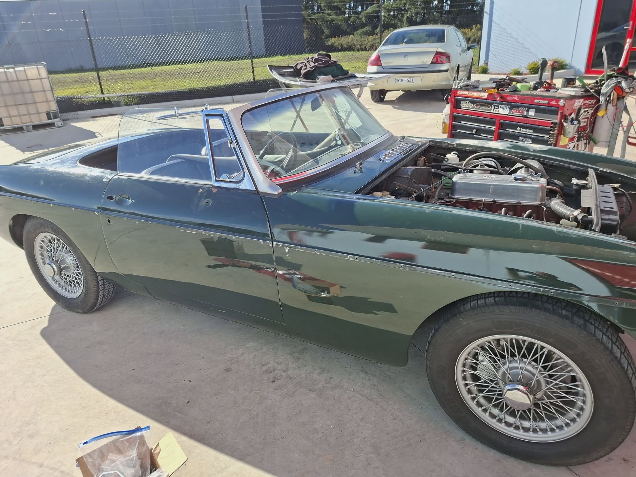 British Racing Green MGB roadster with bonnet open showing classic engine — April Motors workshop