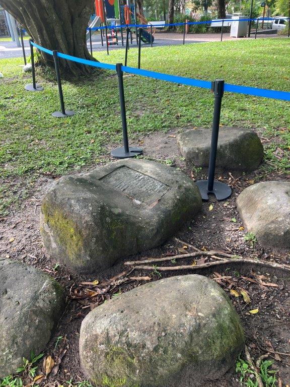 Historic stone heritage marker in a Kuranda park, roped off for preservation