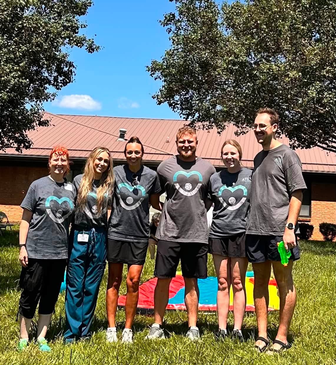 Ahava Services therapy team in ATS shirts gathered outdoors on a sunny day