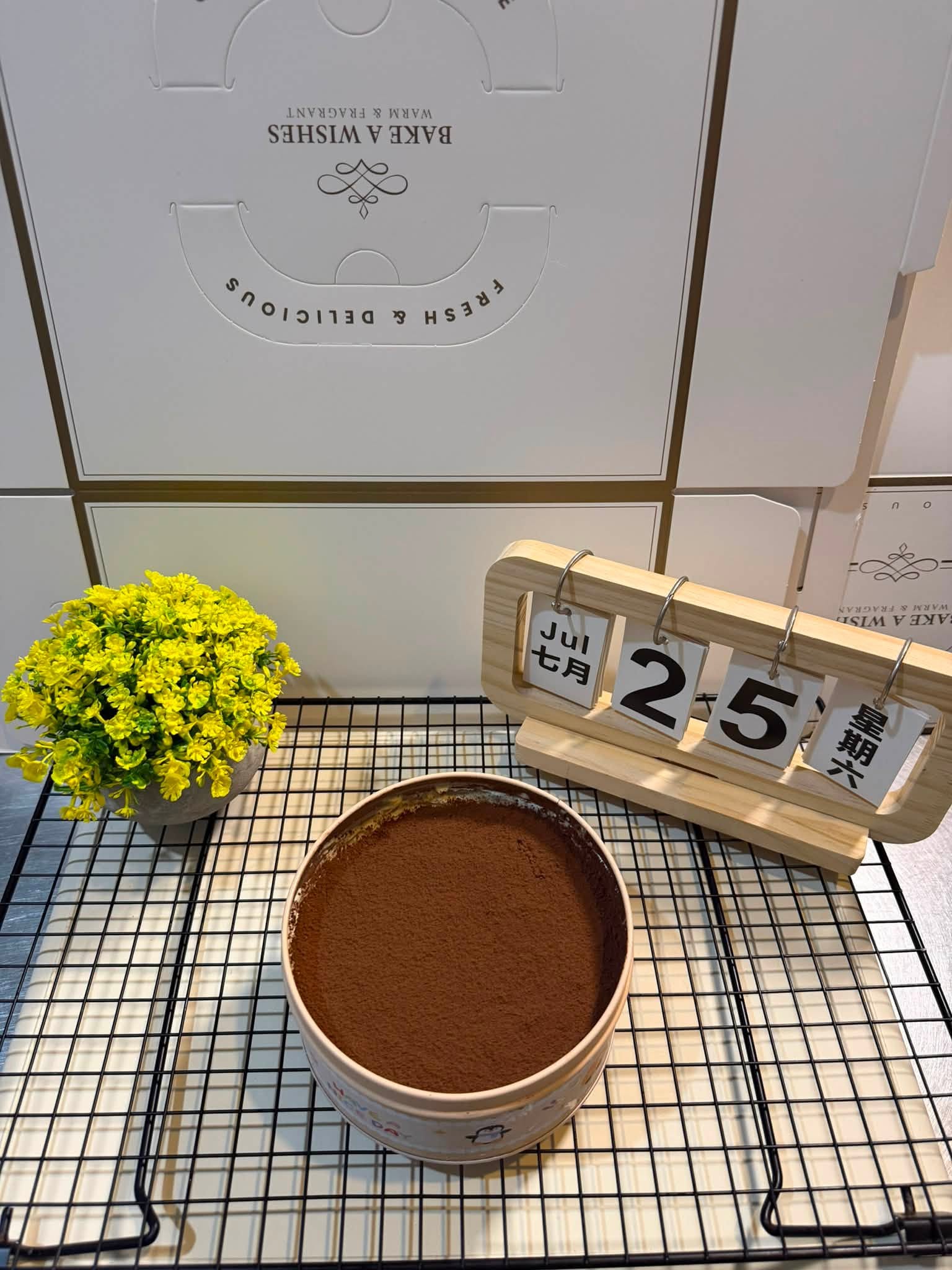 TL Bakehouse tiramisu-style cake dusted with cocoa on a cooling rack