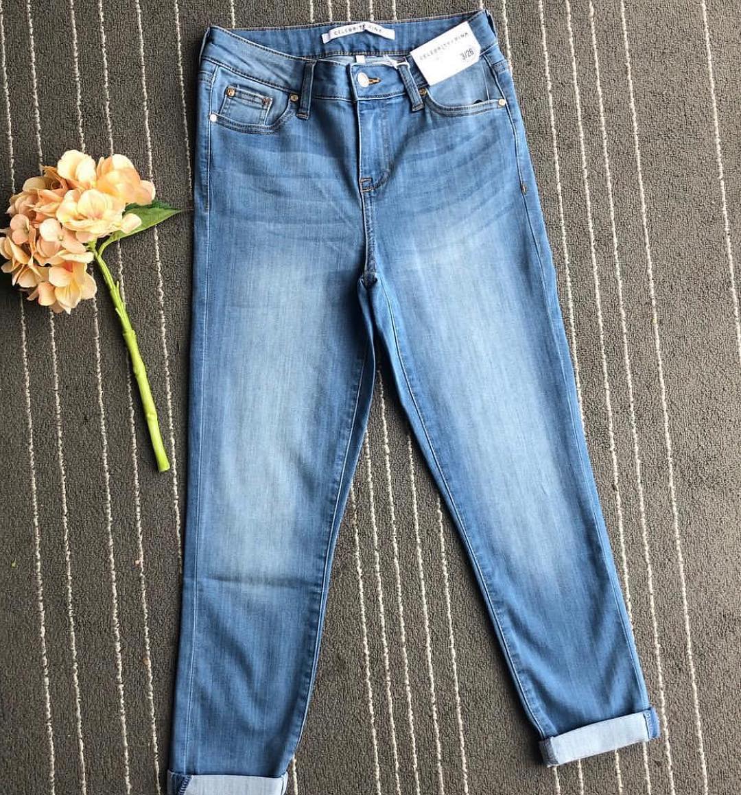 Light-wash jeans laid flat beside a peach flower