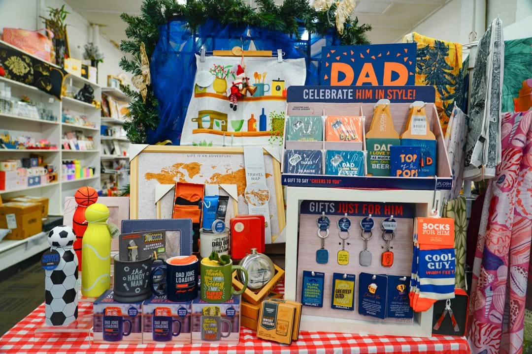 Gift display with mugs, drink bottles, keyrings and socks on a red checked tablecloth