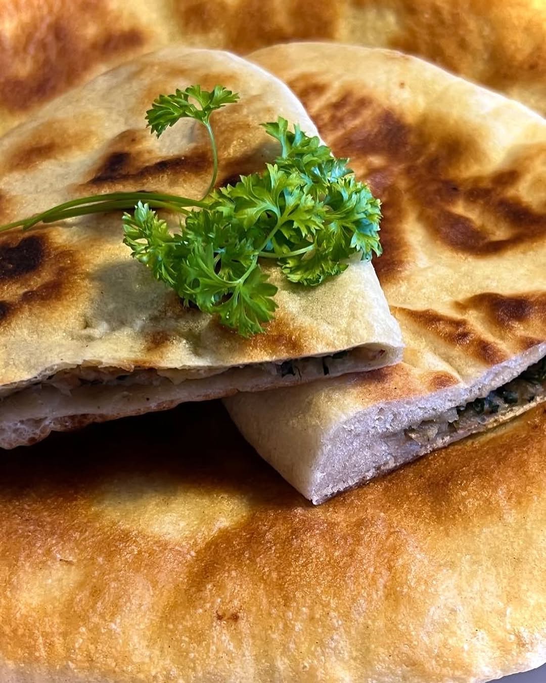 Freshly made gozleme flatbreads with a sprig of curly parsley