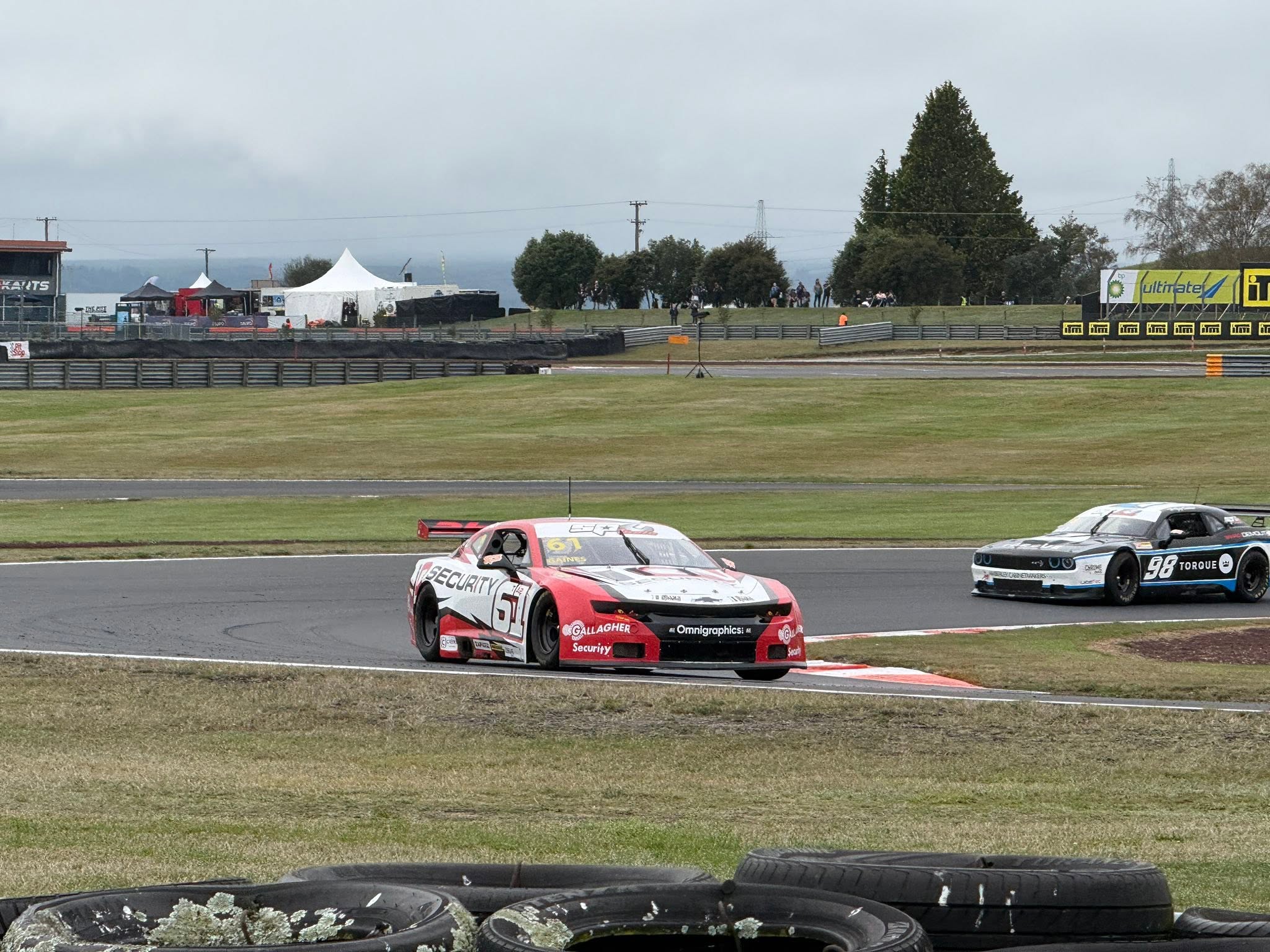 Red and white race car taking a corner with a second car behind