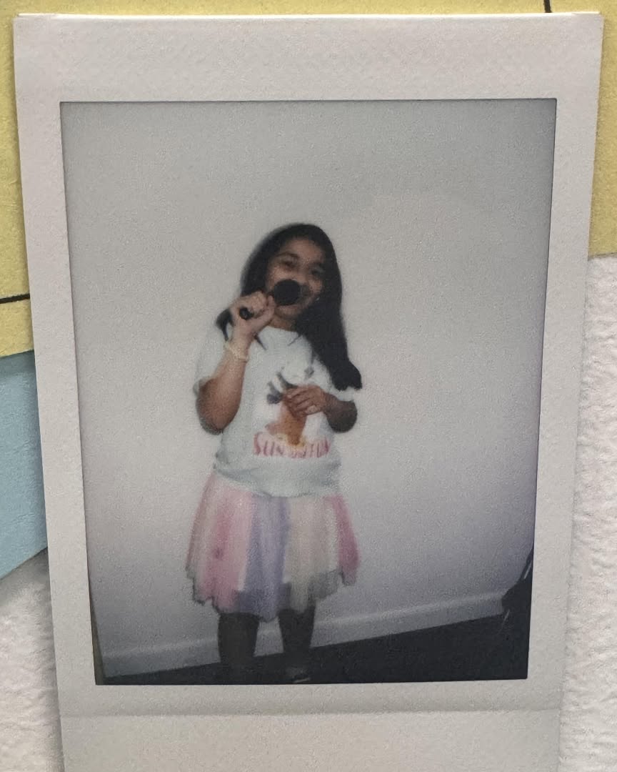 Child in a tutu singing into a microphone