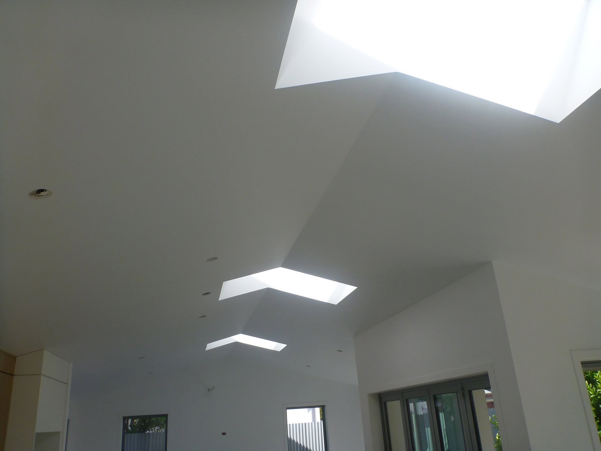Smooth white plastered ceiling with geometric skylights — finished plastering work