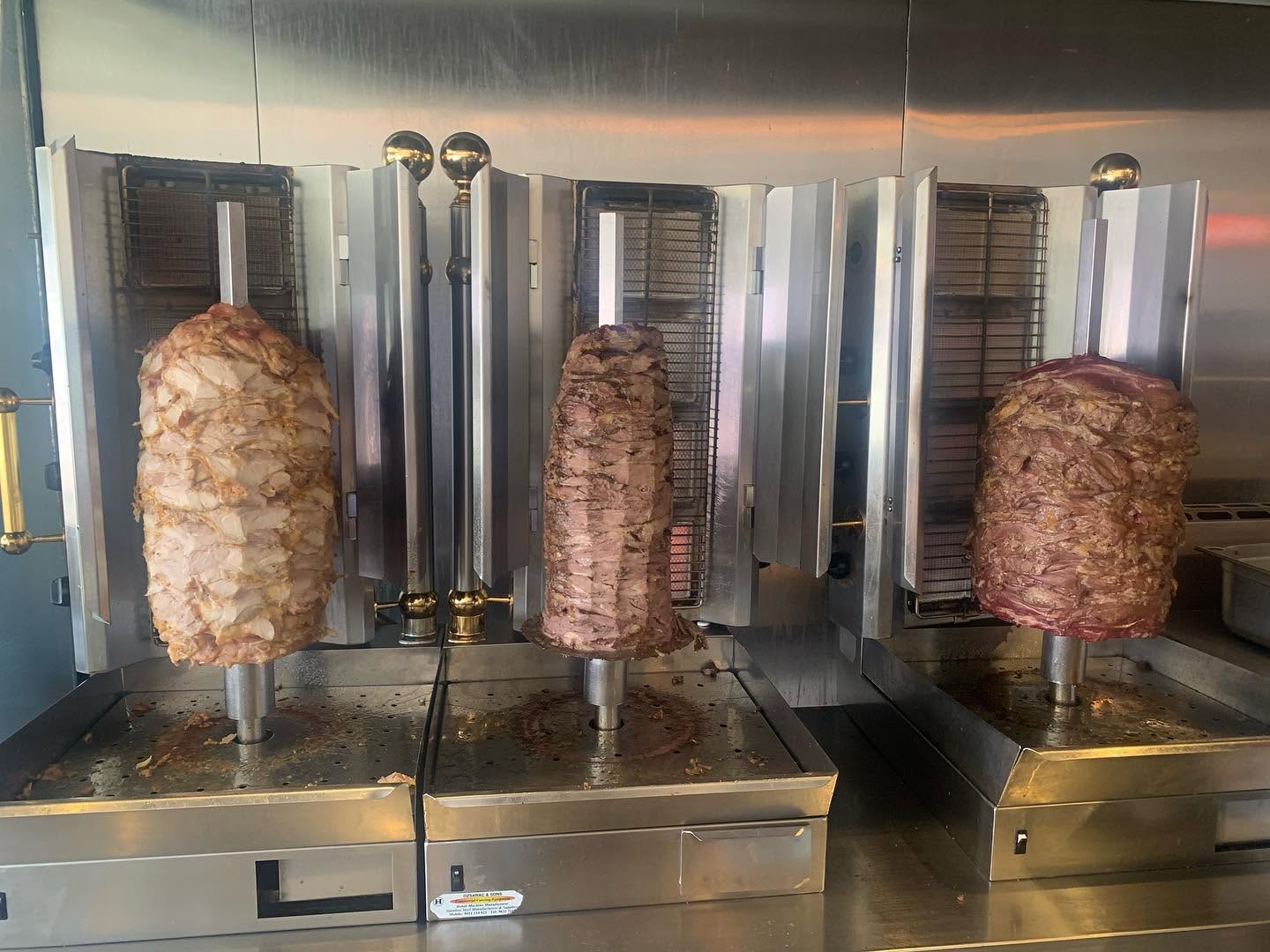 Lamb, chicken and mixed gyros meat roasting on rotisserie spits