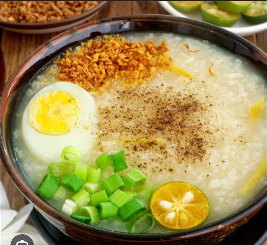 A warm bowl of Filipino congee garnished with egg, spring onion and fried garlic
