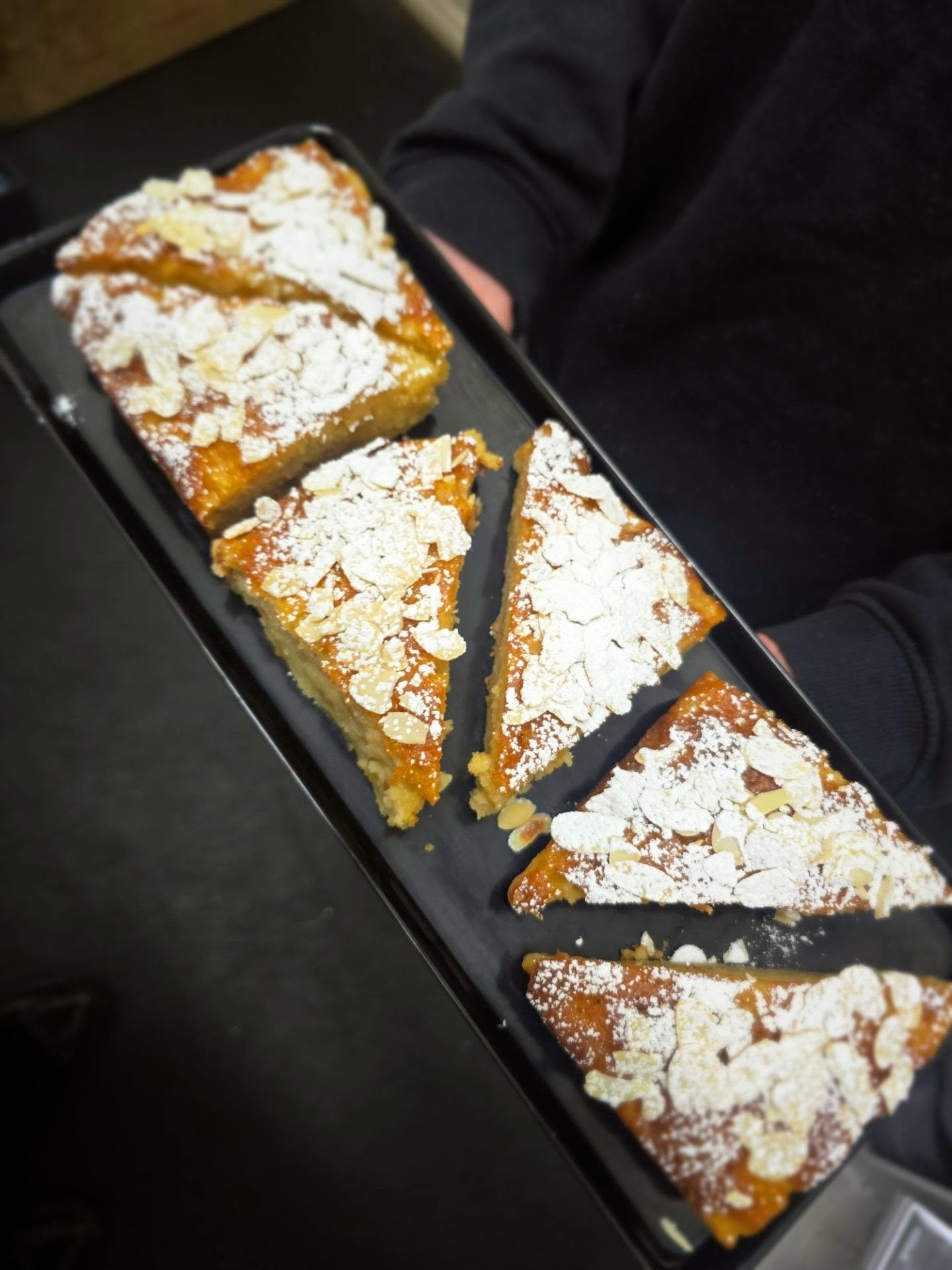 Freshly baked almond cake slices dusted with icing sugar