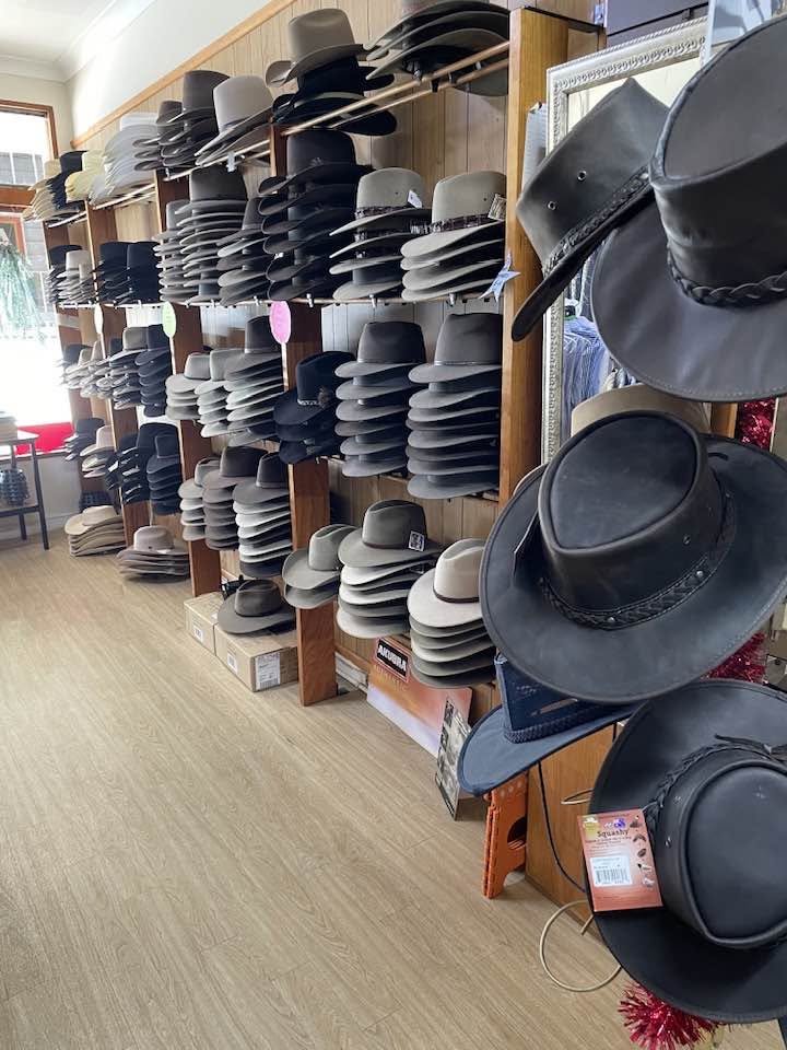 Hats stacked on wooden shelves beside leather hats on display in the store