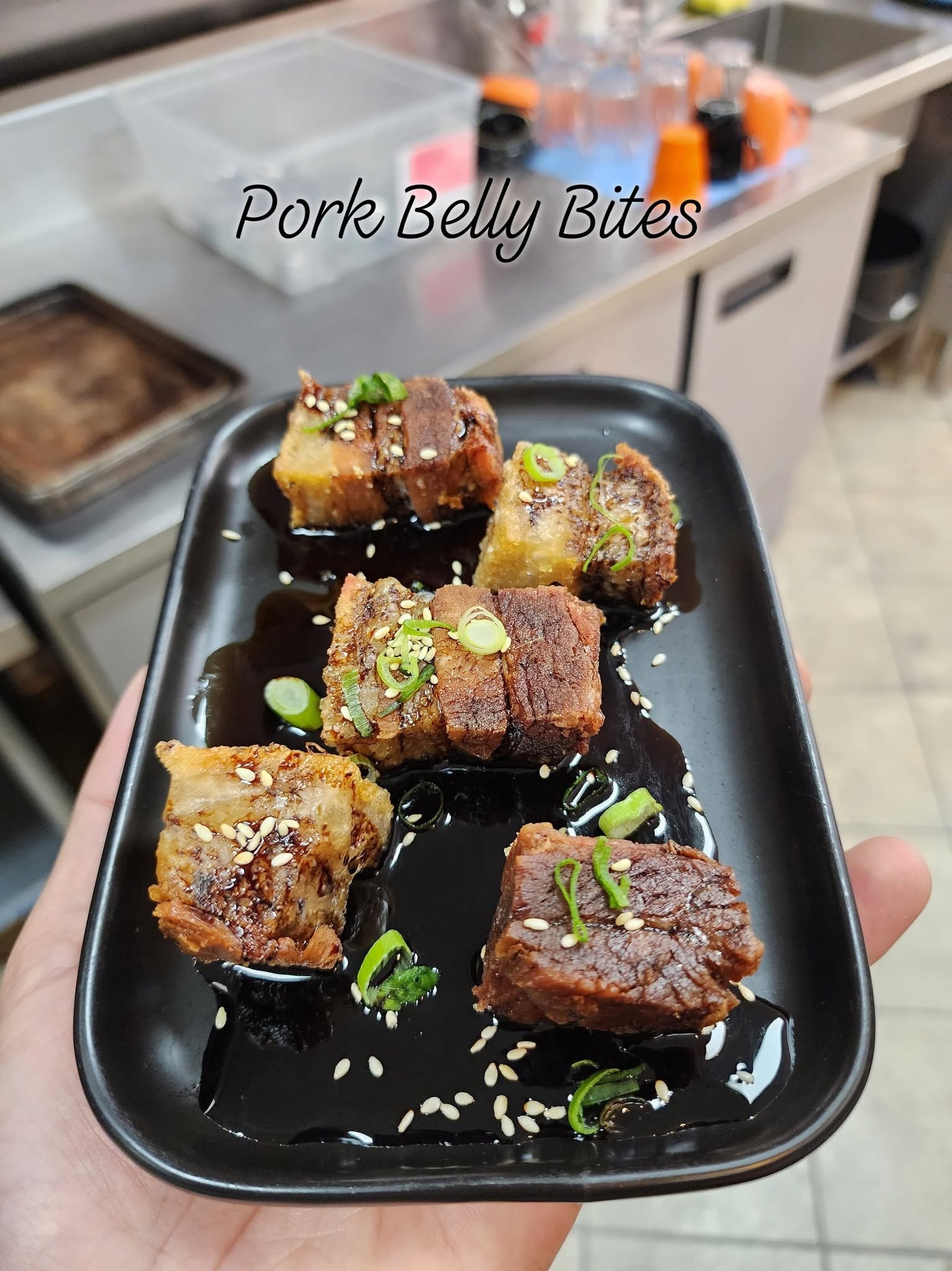 Crispy pork belly bites with a lime caramel sauce, garnished with spring onion and sesame seeds