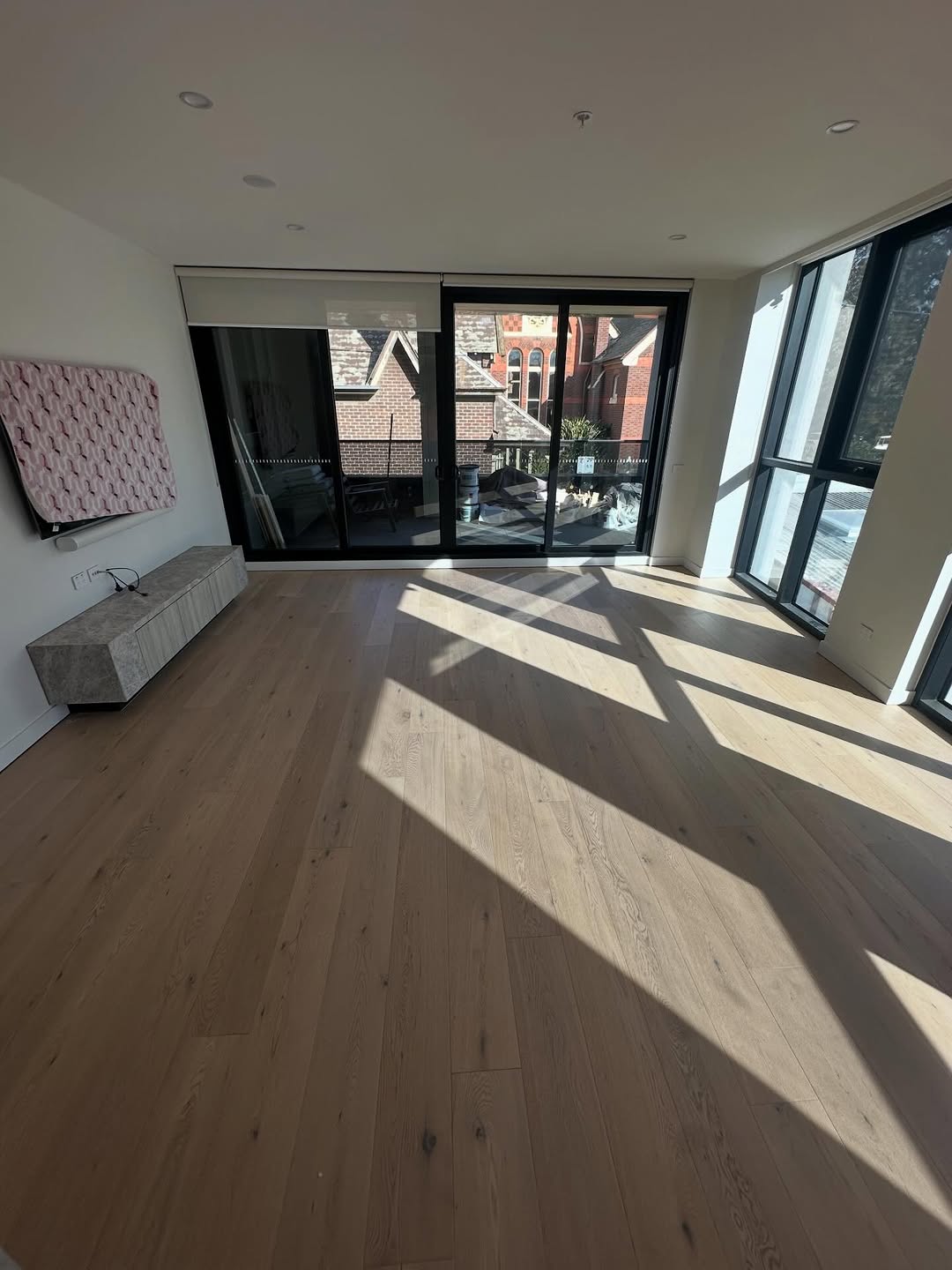Sunlit wide-plank oak timber flooring in a modern apartment with large sliding doors