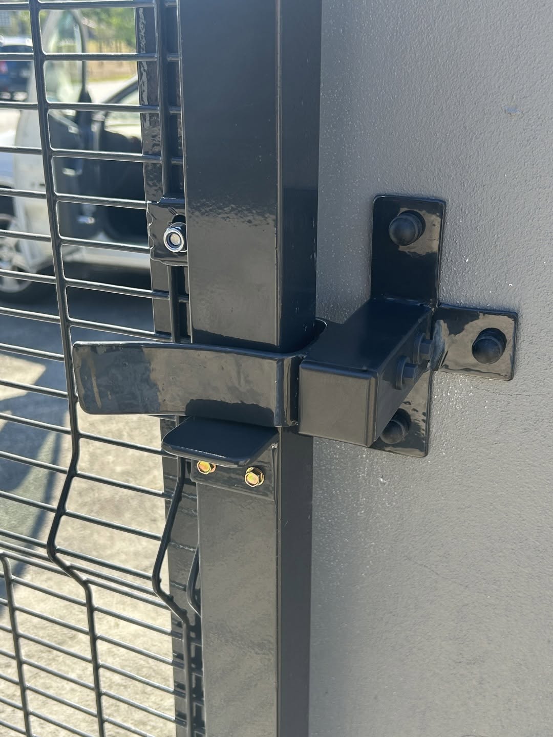 Close-up of black powder-coated gate hinge and bracket hardware
