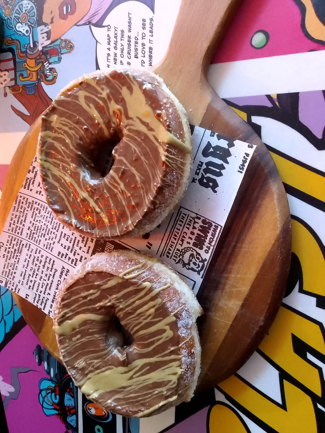 Artisan chocolate-drizzled donuts on a wooden board