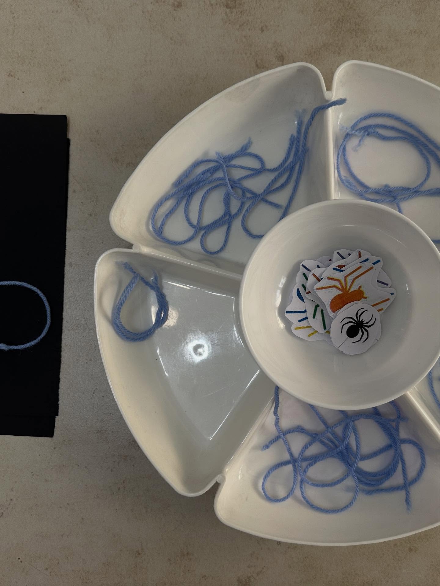 Fine motor skill activity with blue yarn and spider sensory tray