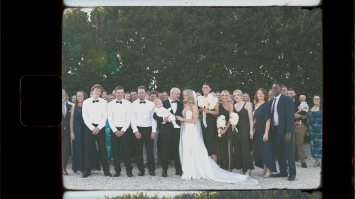 Film grain style group wedding photo showing the full wedding party gathered outdoors