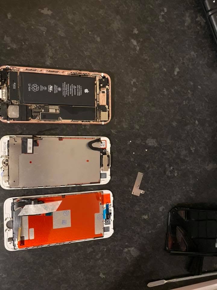 Disassembled smartphone showing battery and internal components on a repair mat