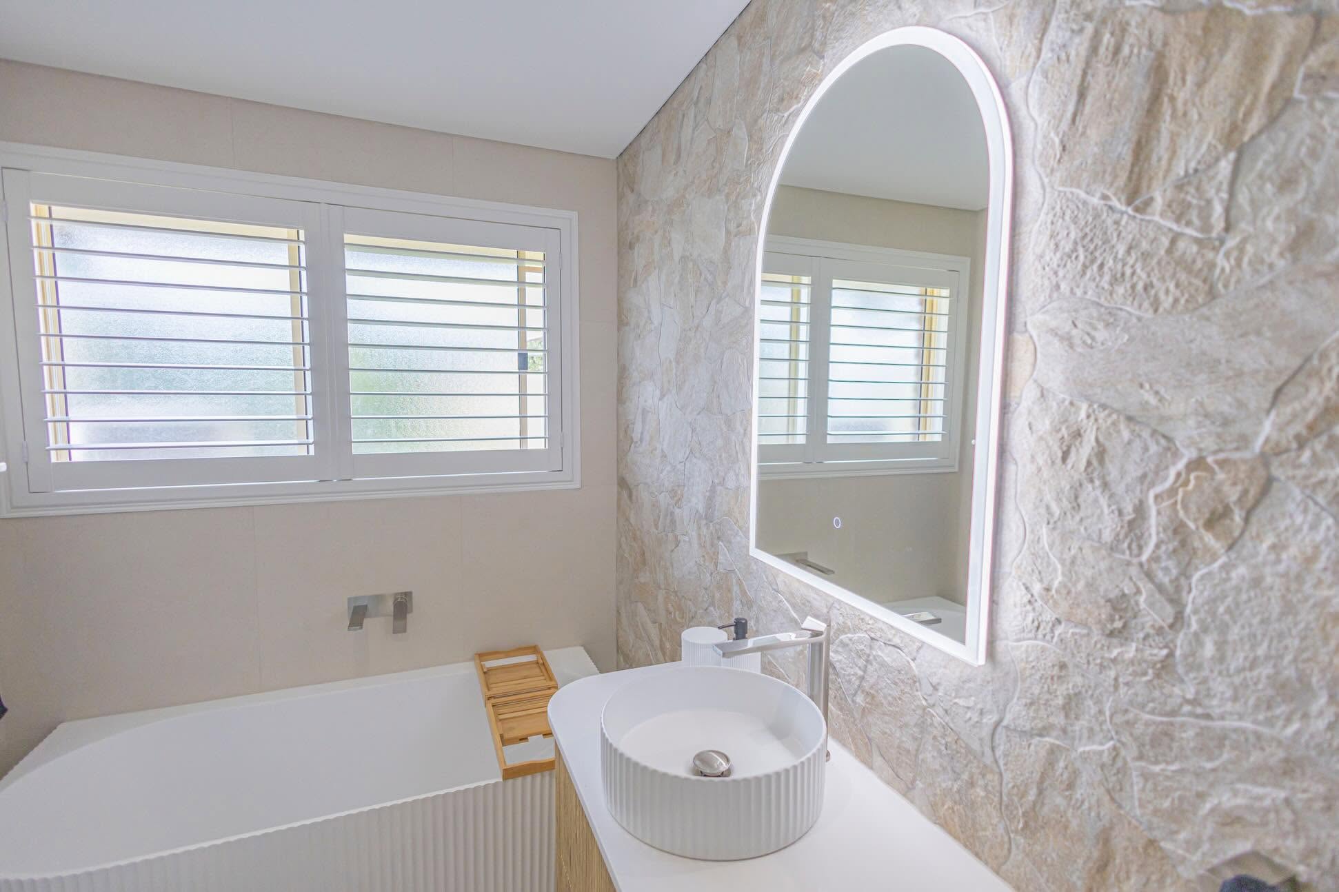 Beautifully tiled bathroom with natural stone feature wall and freestanding bath