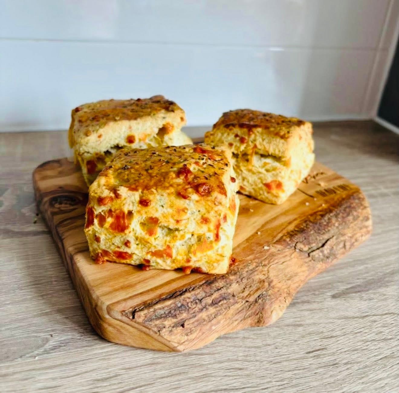 Freshly baked cheese and herb scones on a rustic wooden board — Jiji Bistro & Bar food