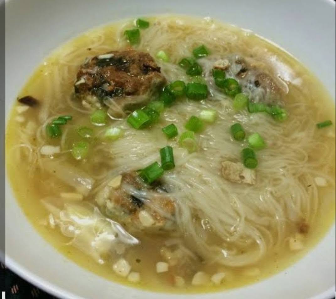 A comforting bowl of Filipino noodle soup with meatballs and spring onion