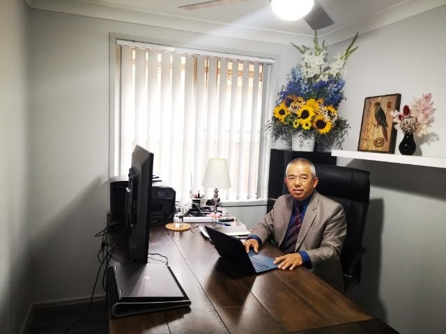 Accountant working at a laptop in a bright office with sunflowers on the desk