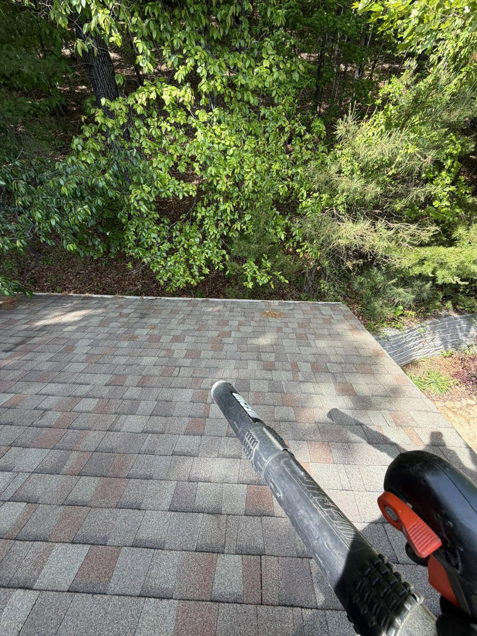 Technician using a leaf blower to clear debris from a tiled roof