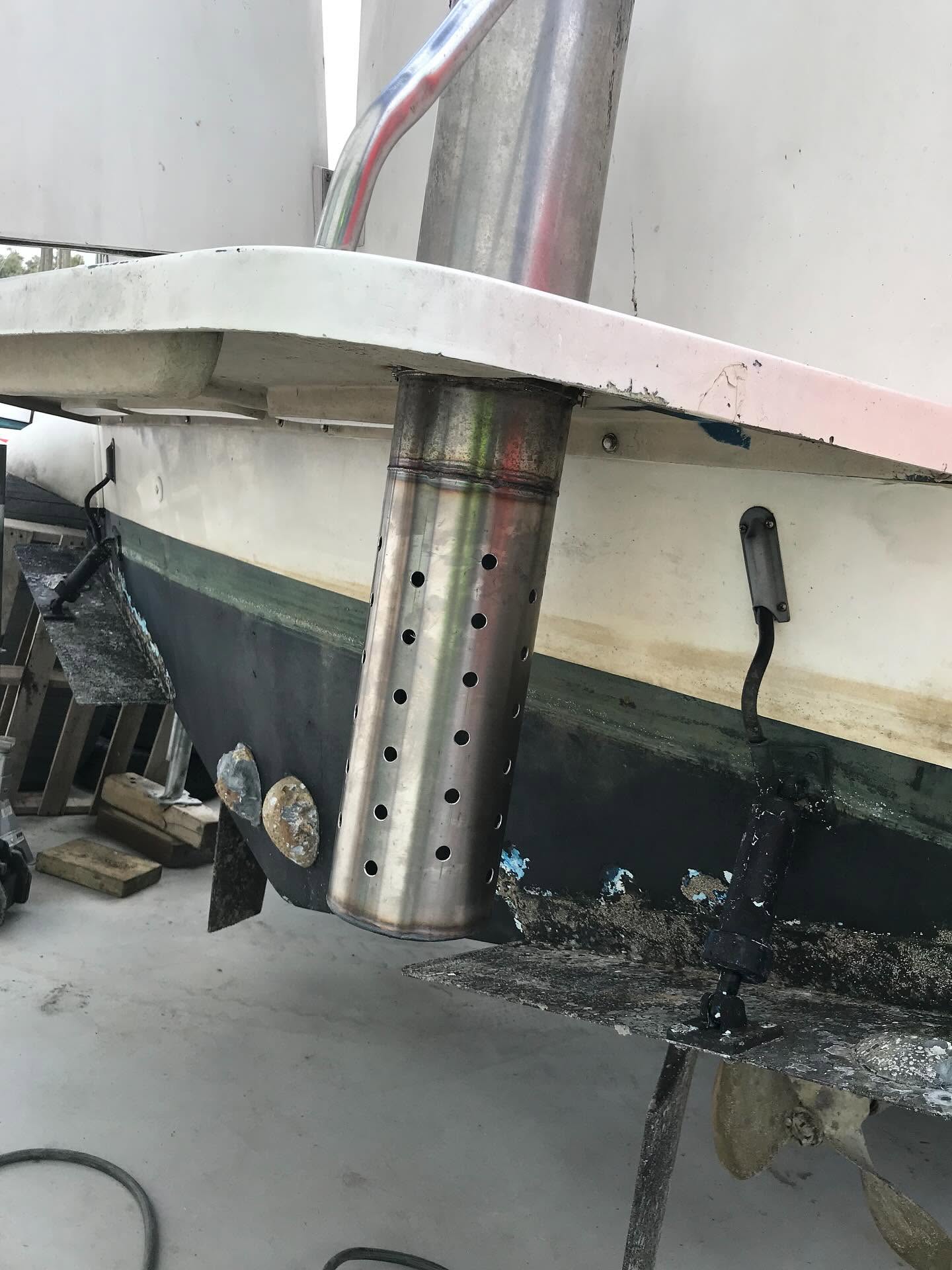 Custom stainless steel exhaust through-hull fitting installed on the hull of a vessel out of the water