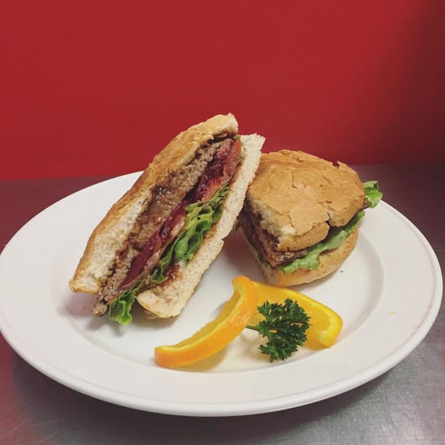 A fresh burger and roll served on a white plate at Tuna Blue Cafe
