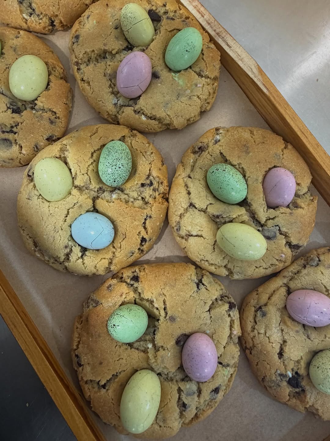 Chocolate chip cookies topped with colourful Easter egg candies on a baking tray